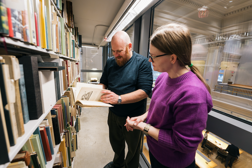 Morgan Swan left and Vi Welker right look over a book from Rauner Library stacks